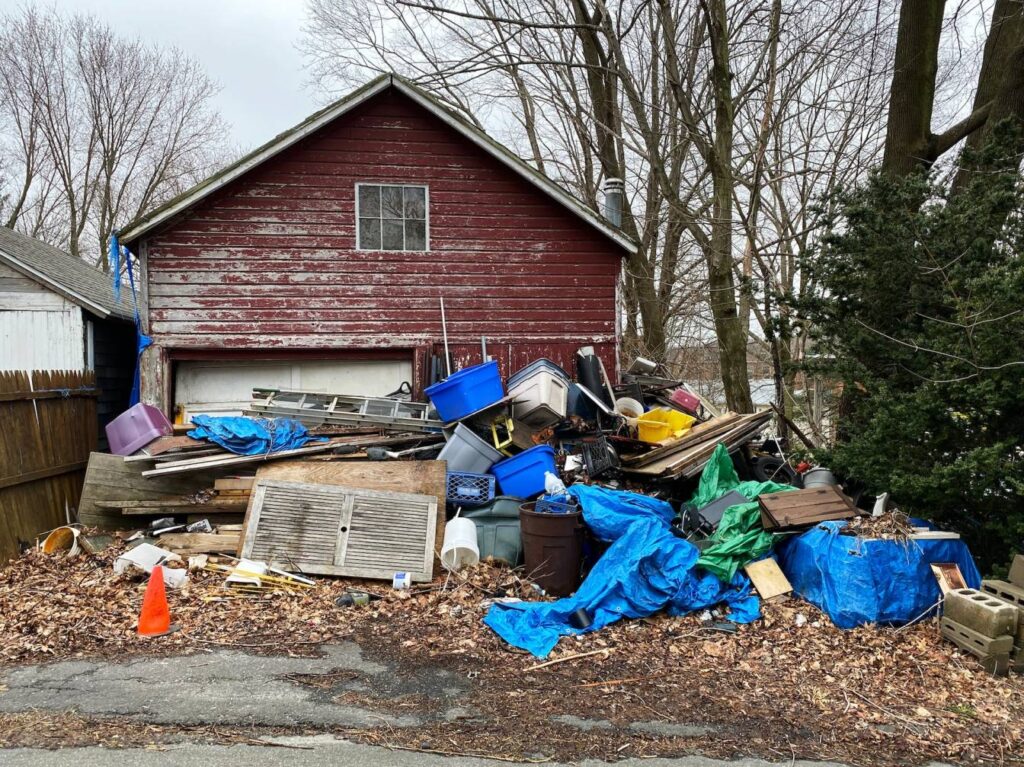 house with piles trash in front yard